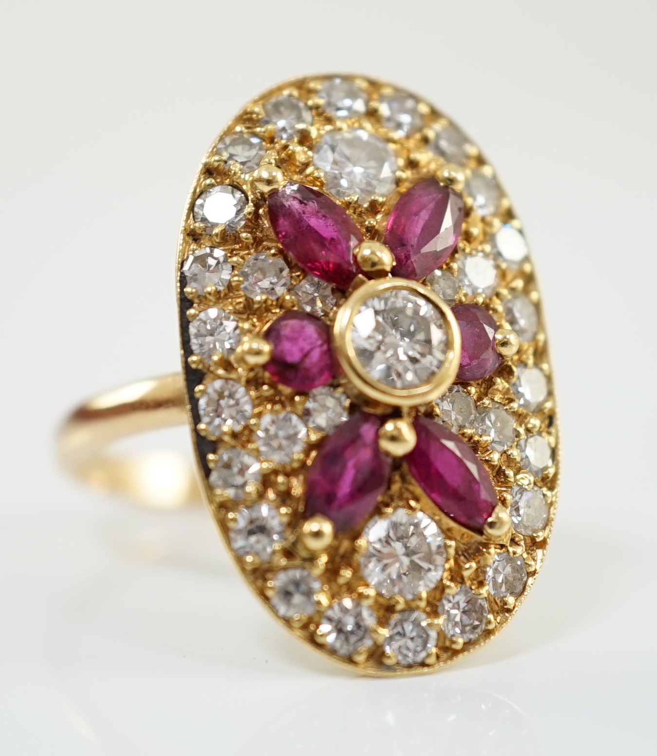 A modern gold, ruby and diamond set oval cluster ring